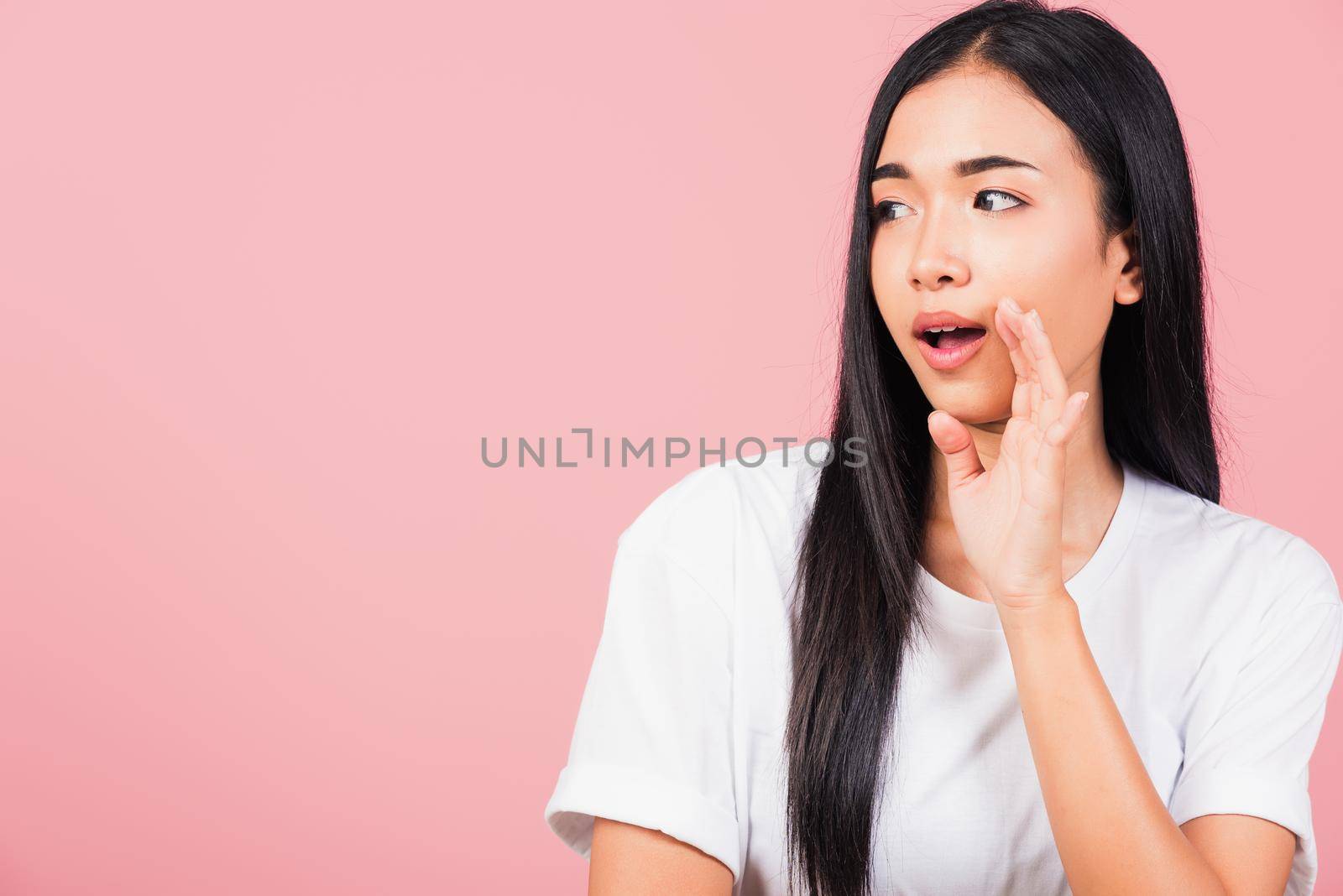 Asian happy portrait beautiful cute young woman teen standing hand on mouth talking whisper secret rumor studio shot isolated on pink background, Thai female looking to side away with copy space