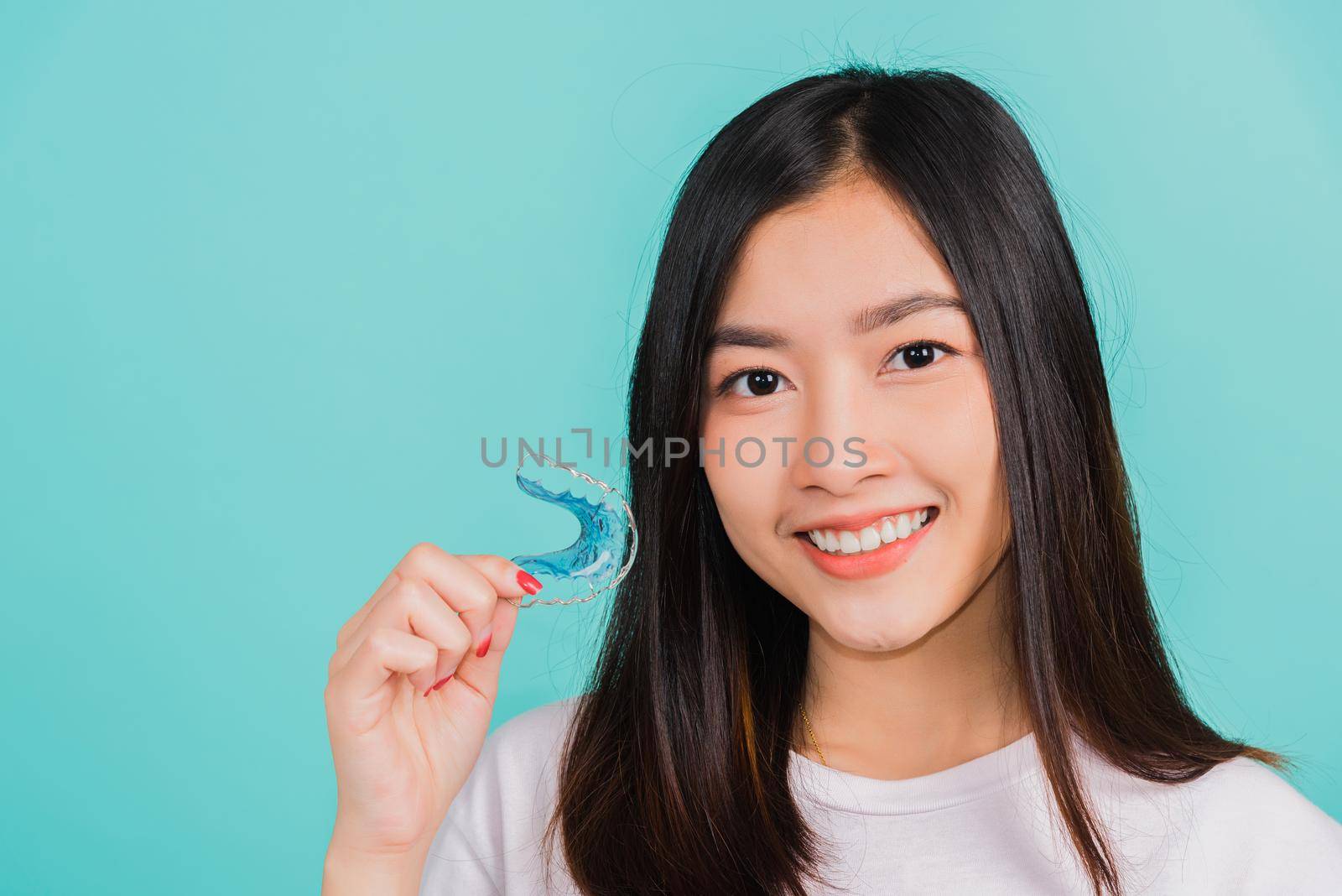 woman smiling holding silicone orthodontic retainers for teeth by Sorapop