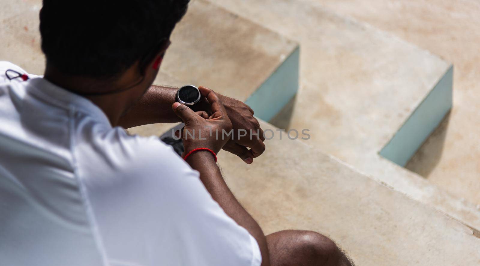 Close up Asian young athlete sport runner black man wear modern time smart watch he sitting resting before training running at the outdoor street health park, healthy exercise before workout concept