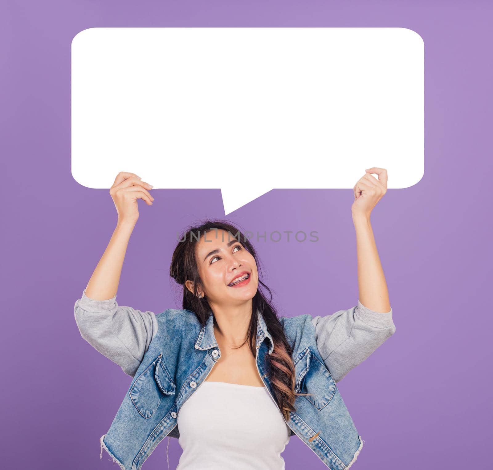 woman smiling excited wear denims hold empty speech bubble sign by Sorapop