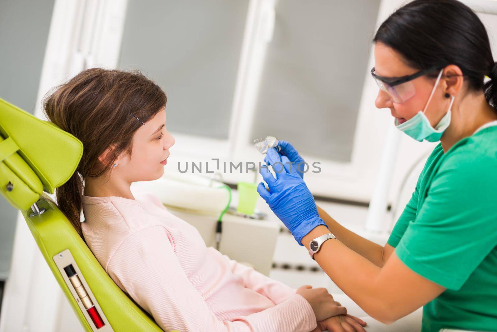 Dentist is teaching little girl about braces.