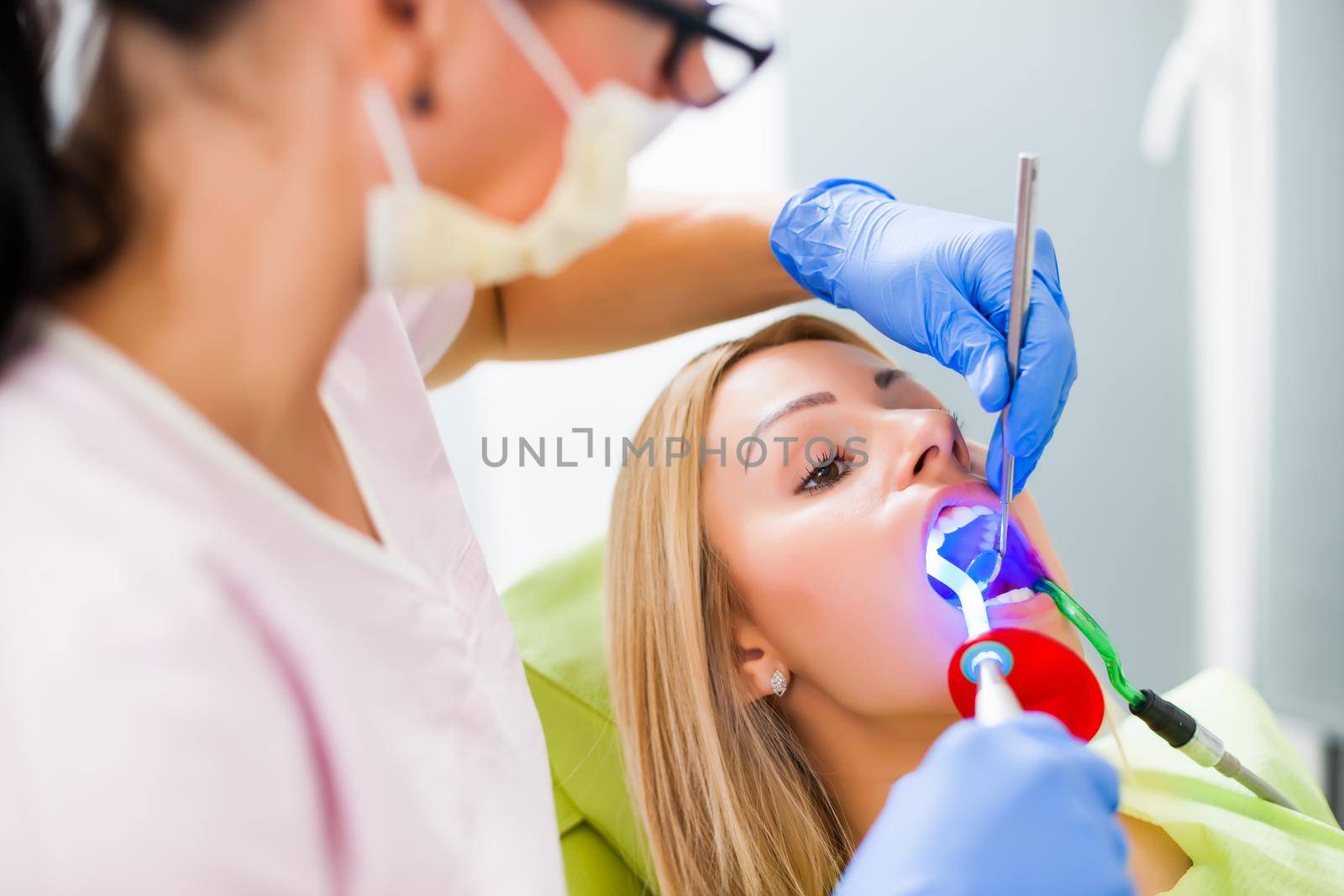 Young woman at dentist. Dentist is repairing her teeth.