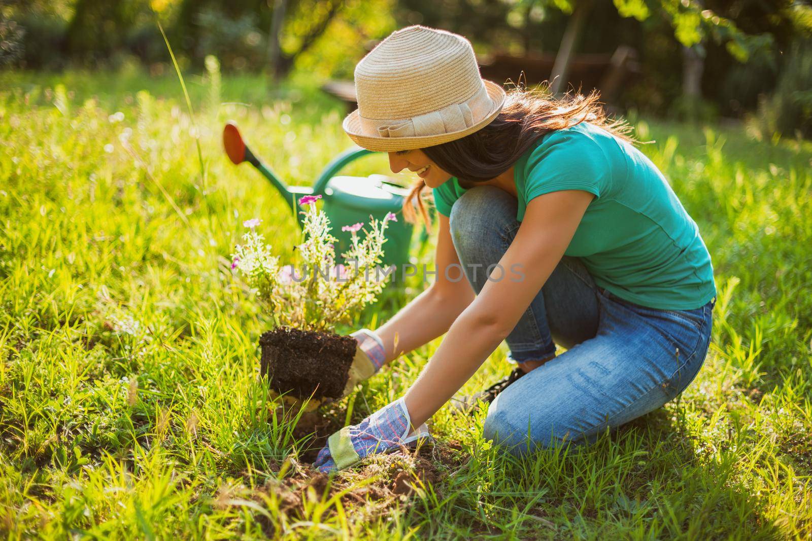 Young happy woman is planting a flower in her garden.