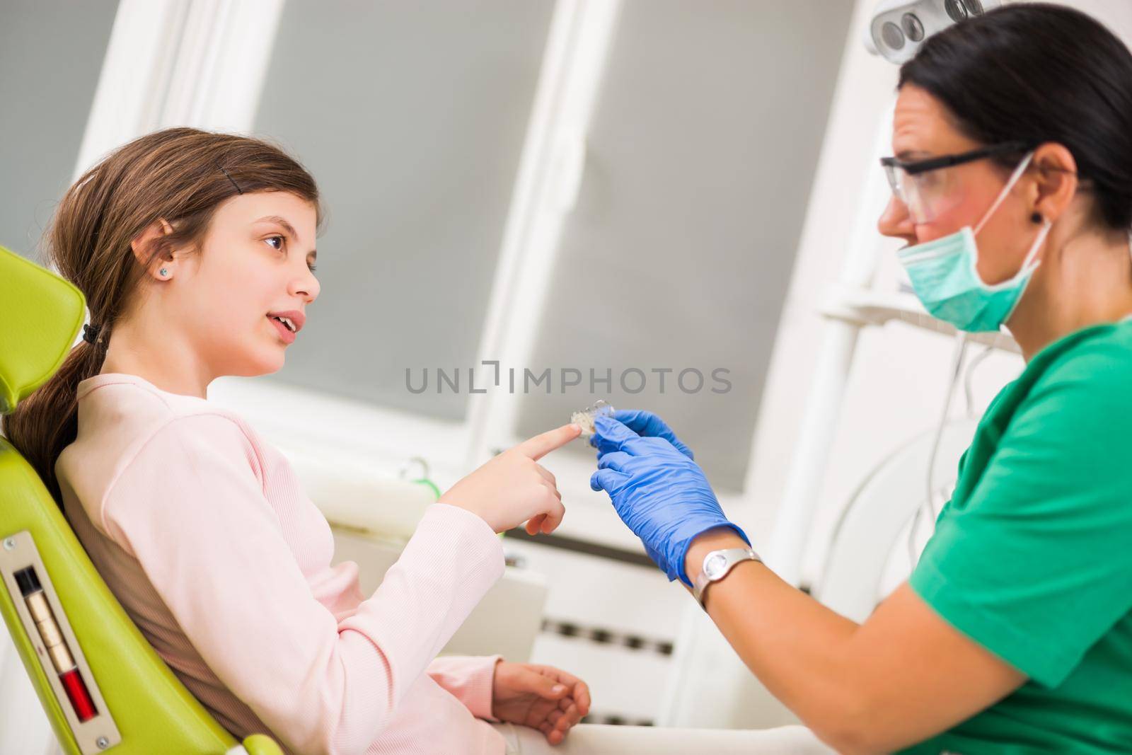 Dentist is teaching little girl about braces.