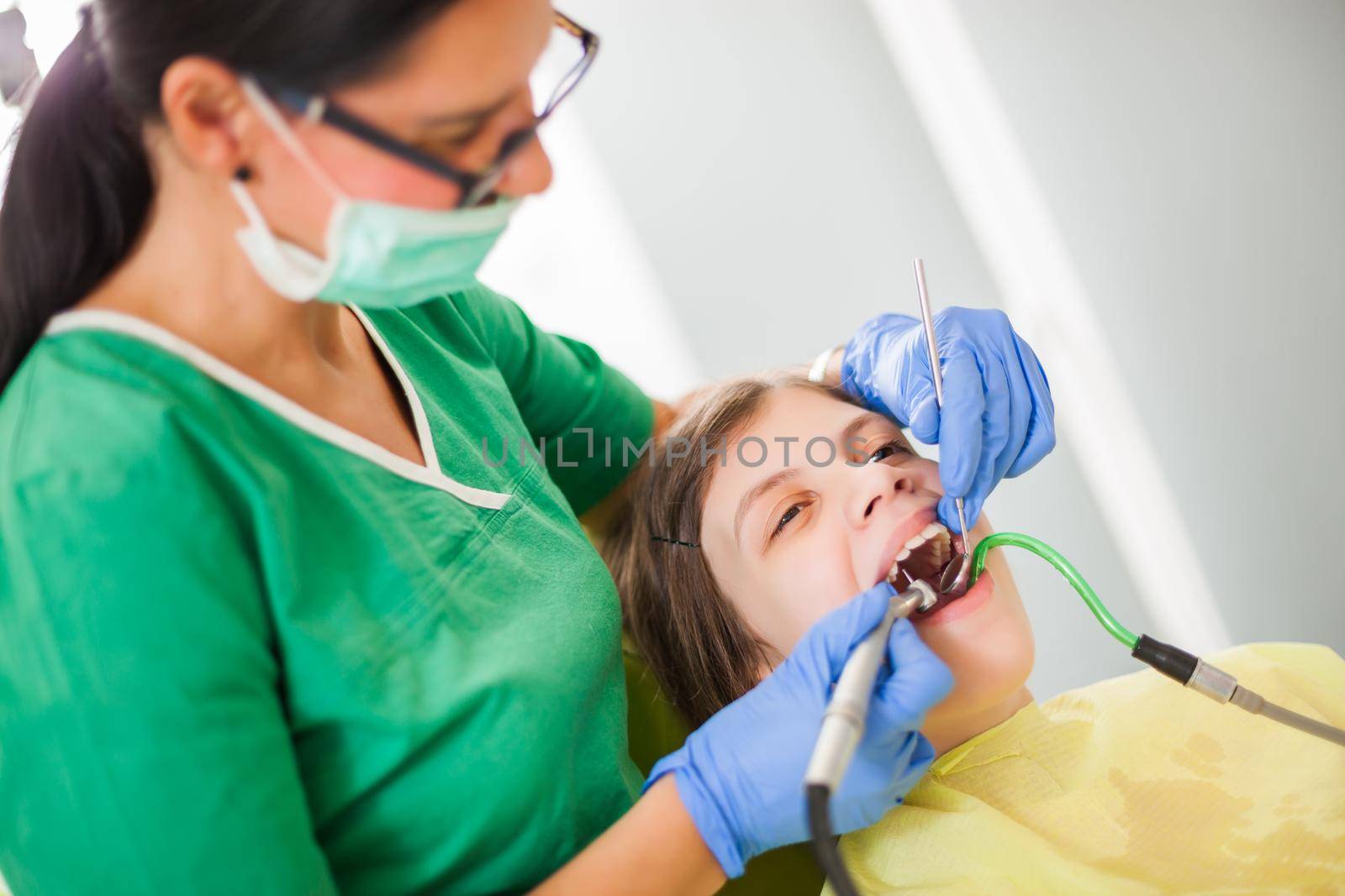 Dentist is repairing teeth of a little girl.