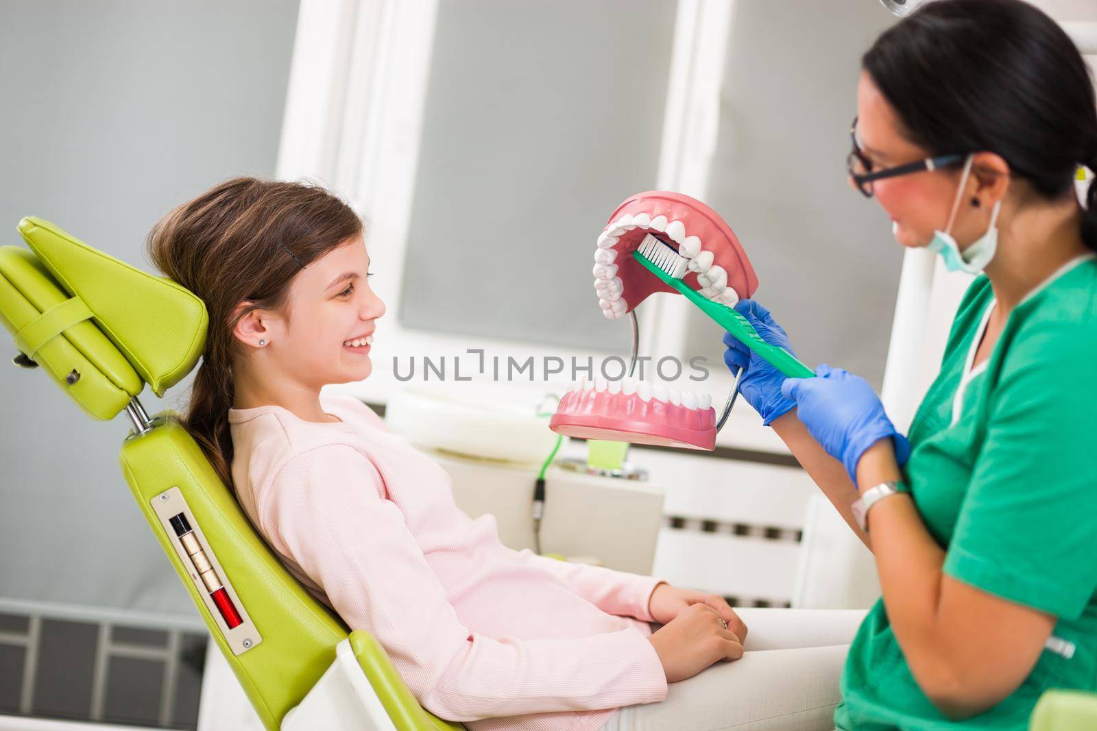 Dentist is teaching little girl about oral hygiene.