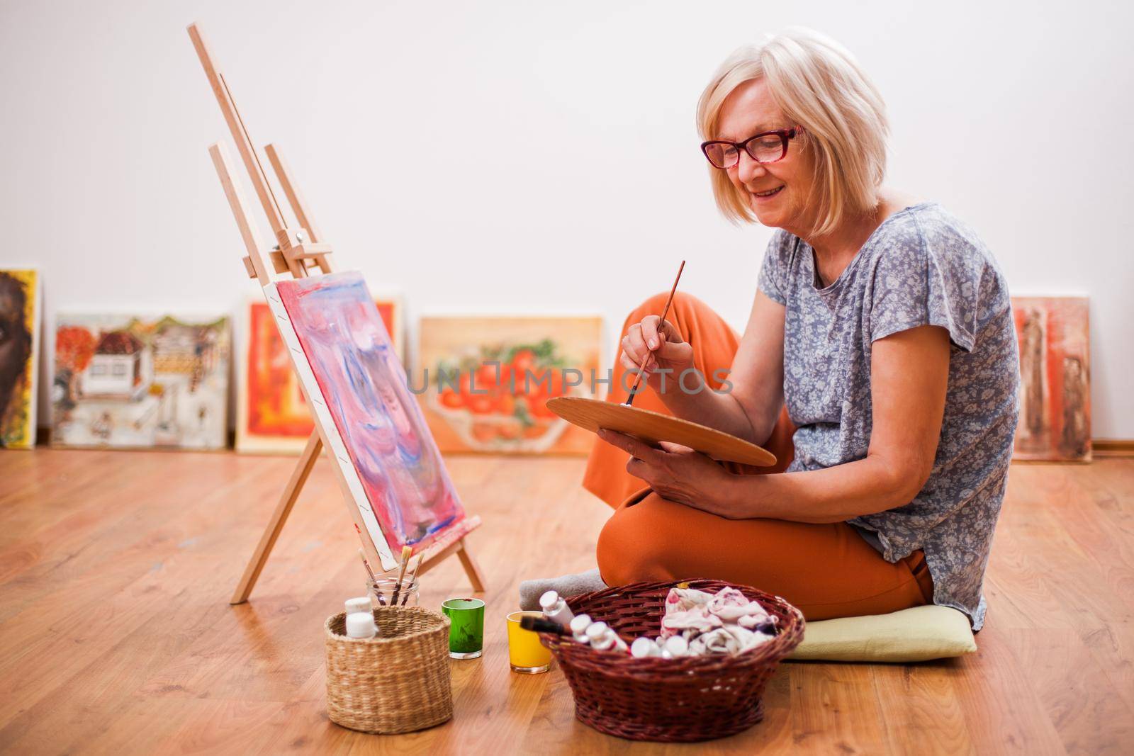 Elderly woman is painting in her home. Retirement hobby.