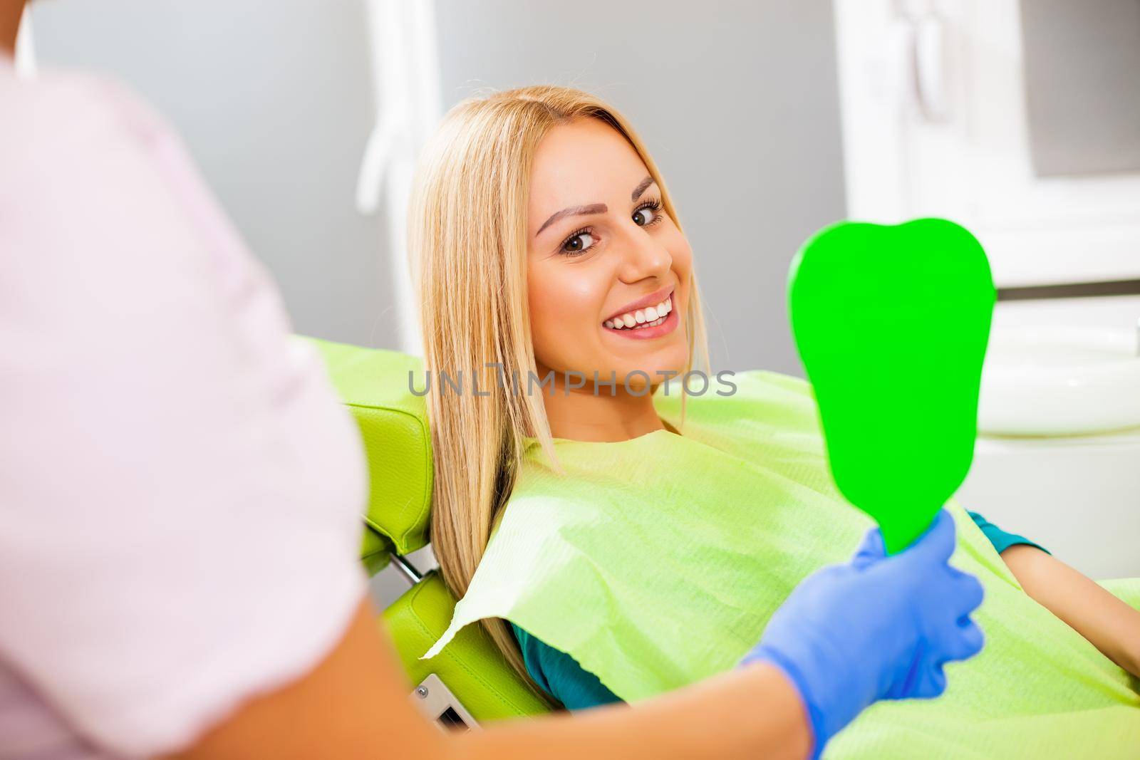 Young woman looking at her teeth after successful dental treatment.