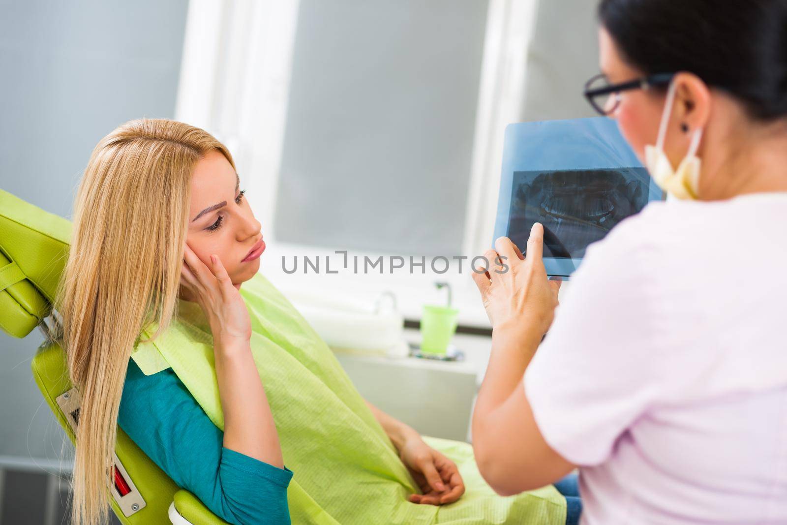 Young woman at dentist. Examining x-ray image.