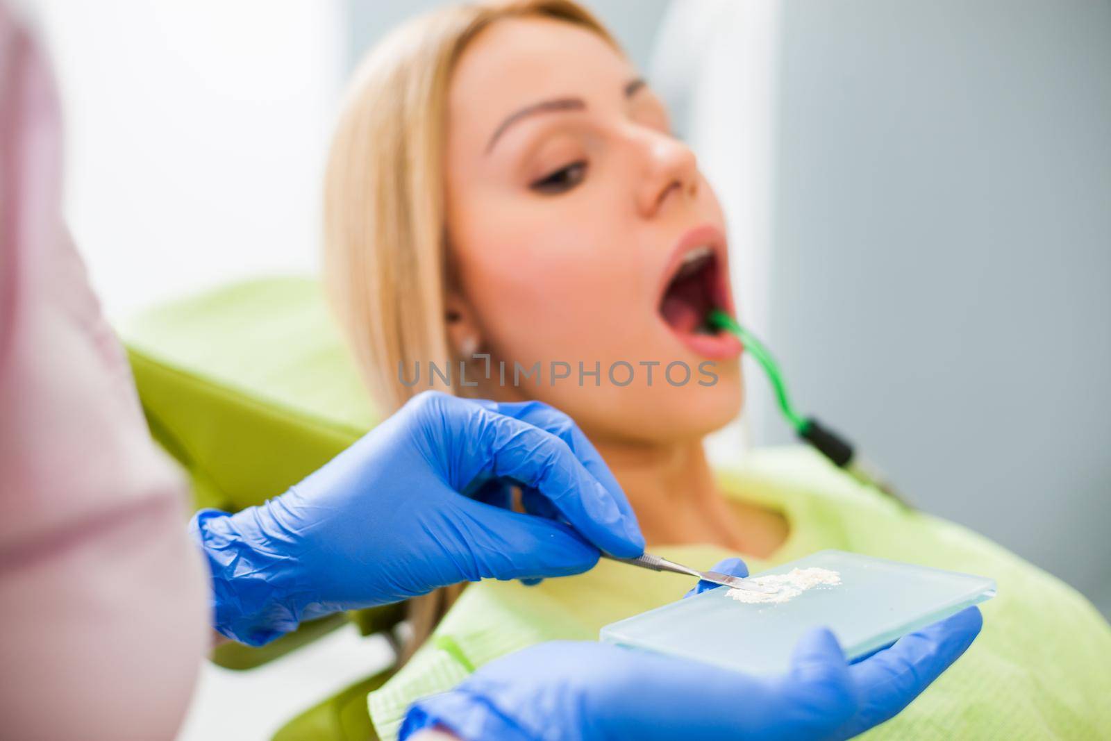 Young woman at dentist. Dentist is repairing her teeth.