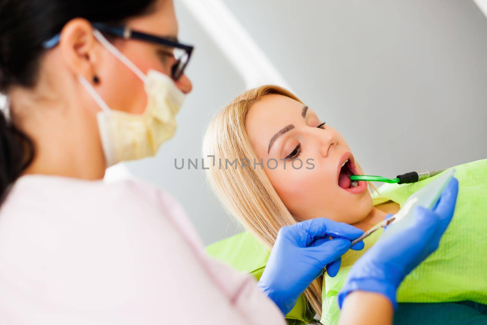 Young woman at dentist. Dentist is repairing her teeth.