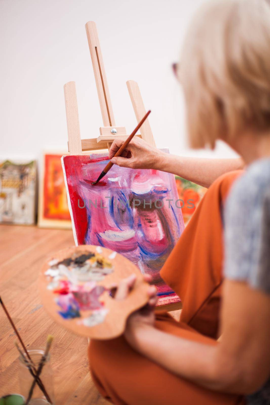 Elderly woman is painting in her home. Retirement hobby.