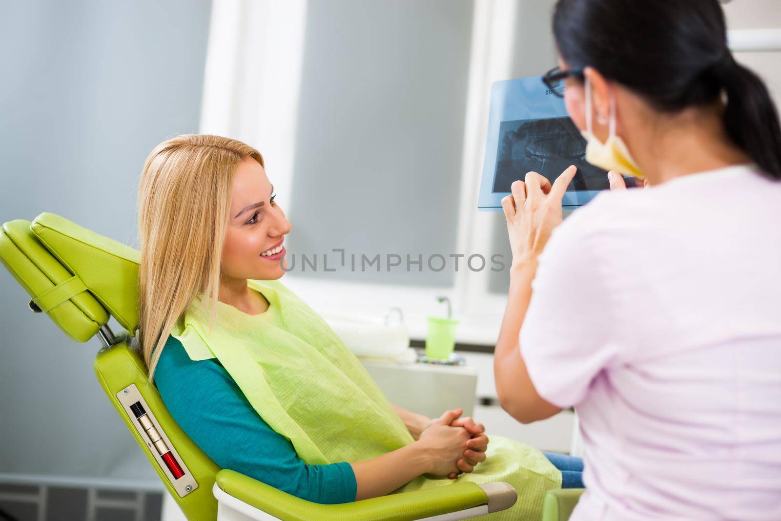 Young woman at dentist. Examining x-ray image.