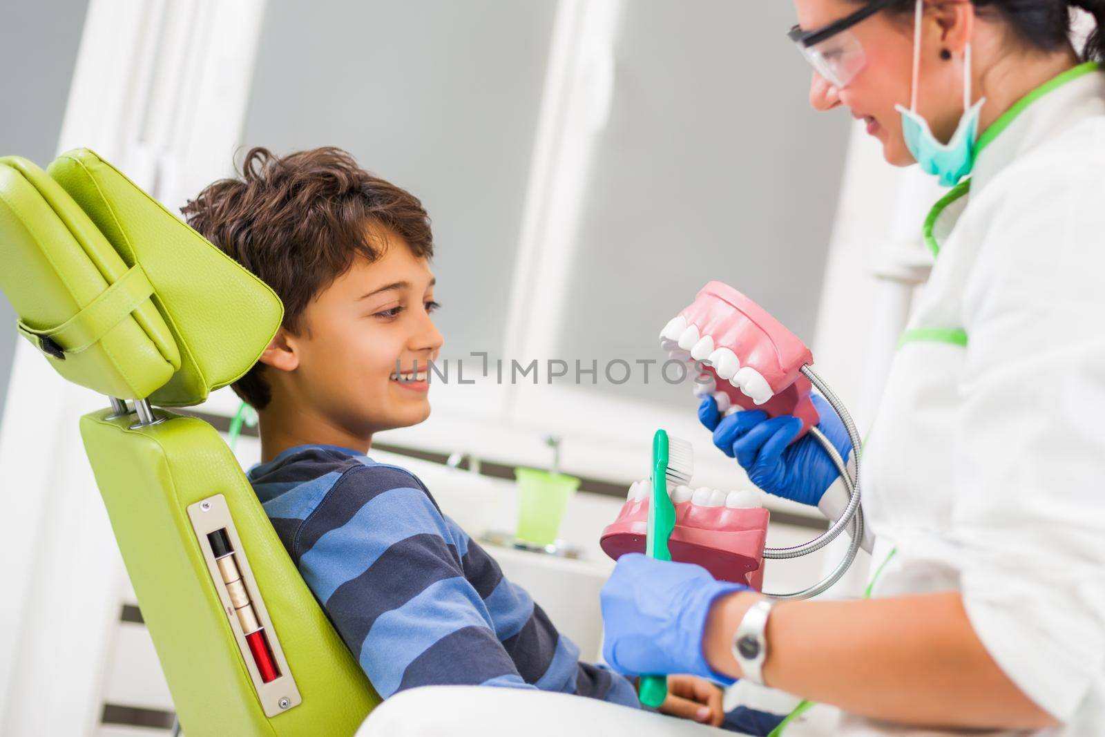 Dentist is teaching little boy about oral hygiene.