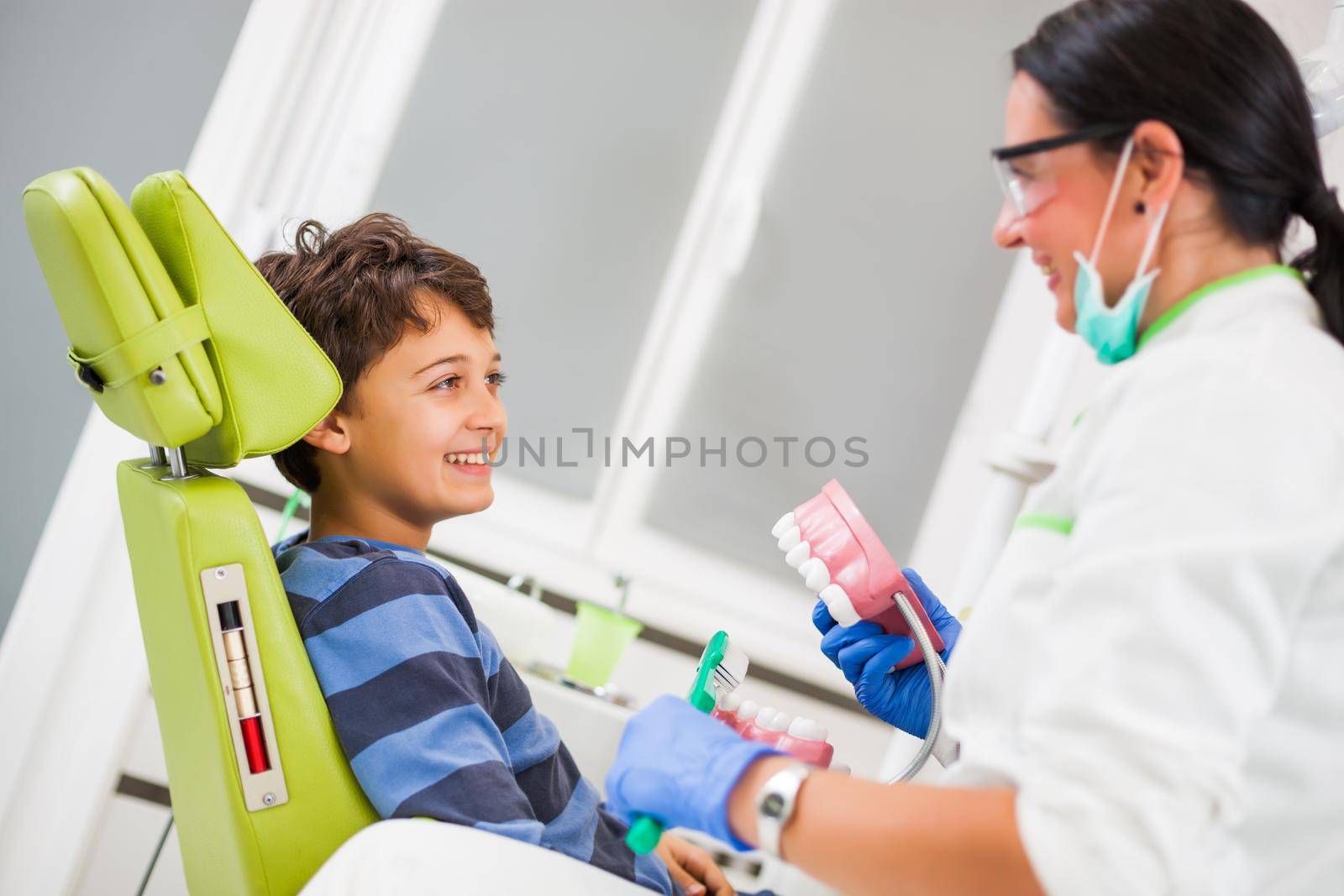 Dentist is teaching little boy about oral hygiene.