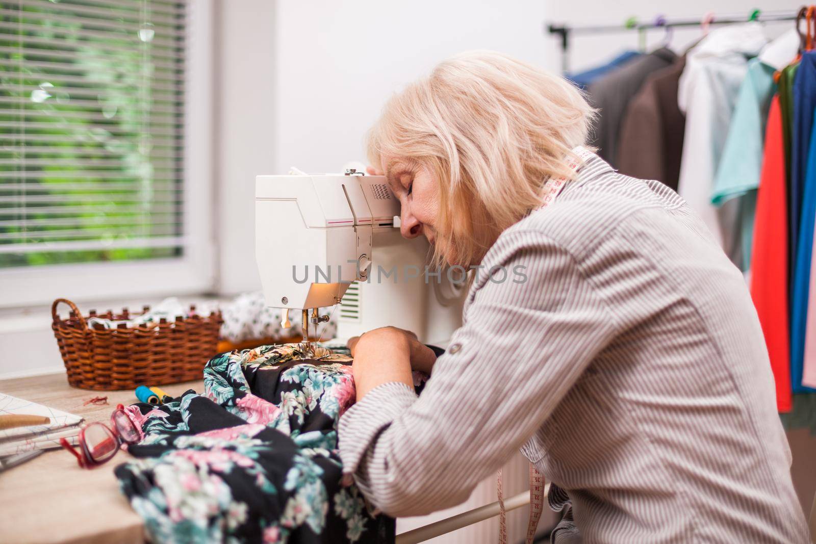 Adult woman is sewing in her studio. She is tired.