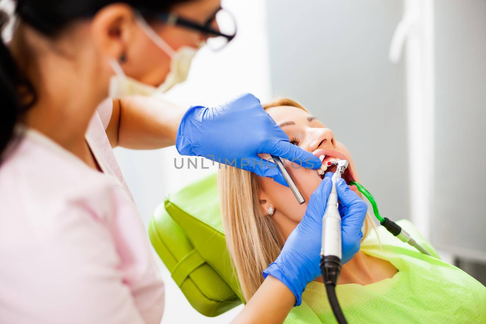 Young woman at dentist. Dentist is repairing her teeth.