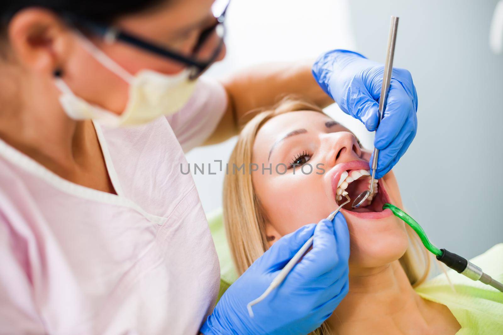 Young woman at dentist. Dentist is repairing her teeth.