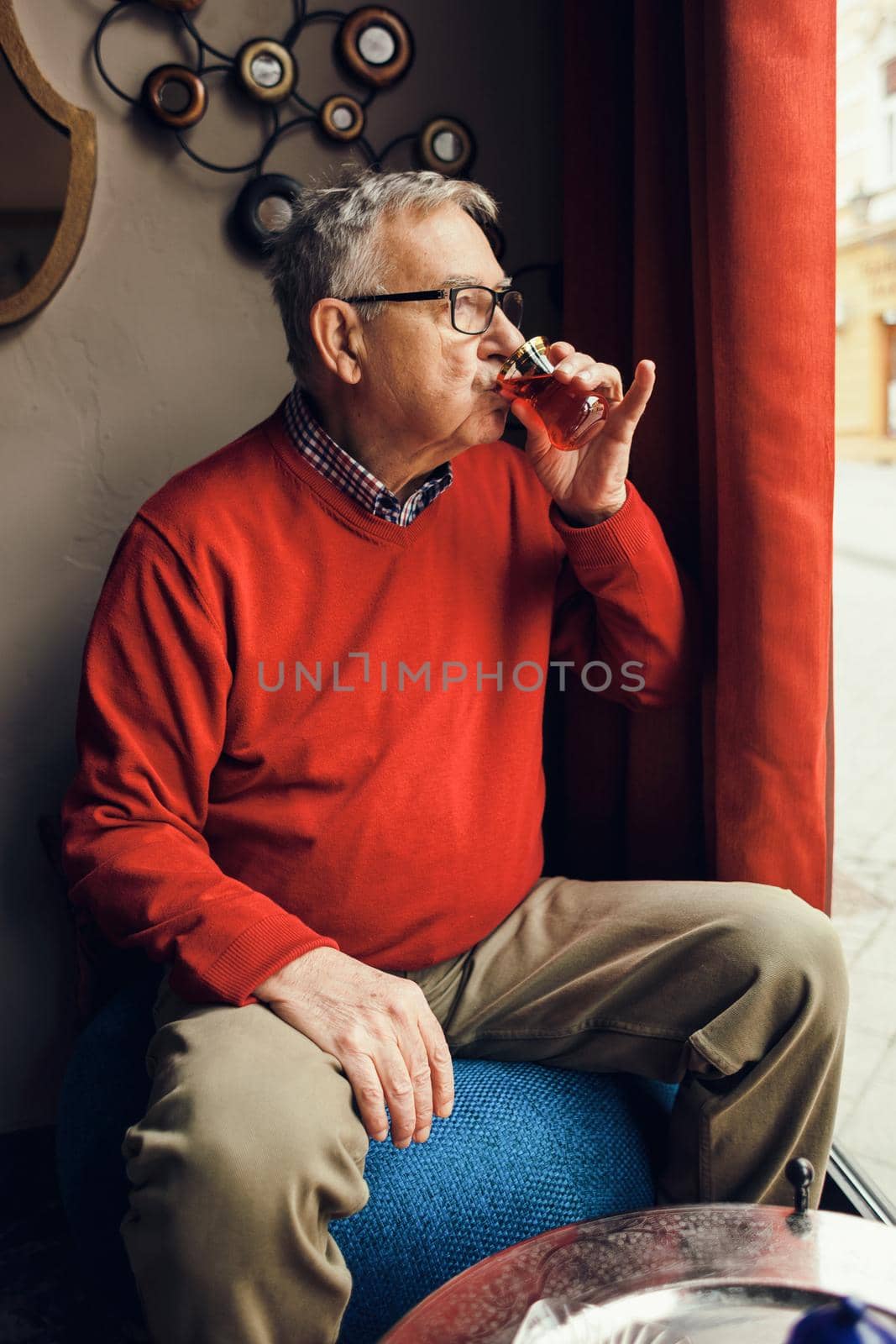 Senior man is drinking tea in a cafe.