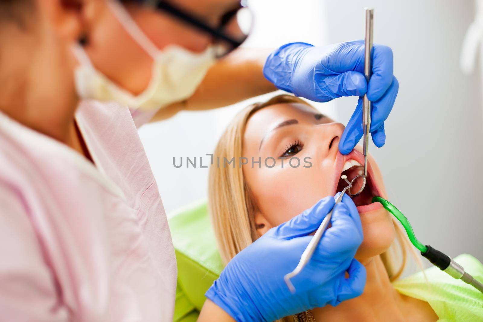Young woman at dentist. Dentist is examining her teeth.