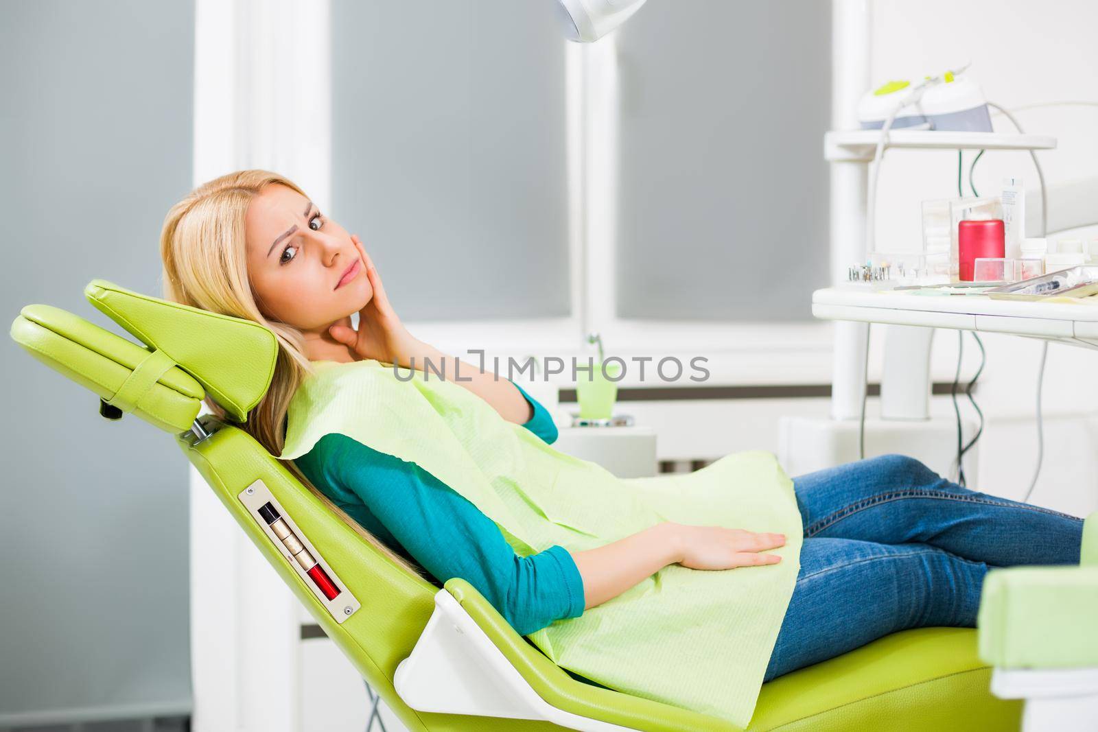 Young woman at dentist. She has toothache.