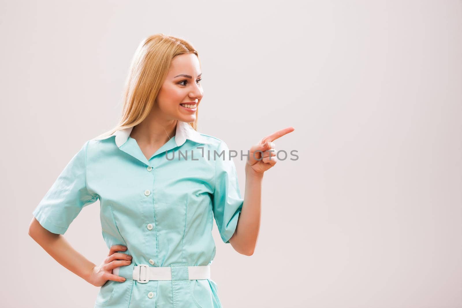 Portrait of young nurse who is pointing at advert.