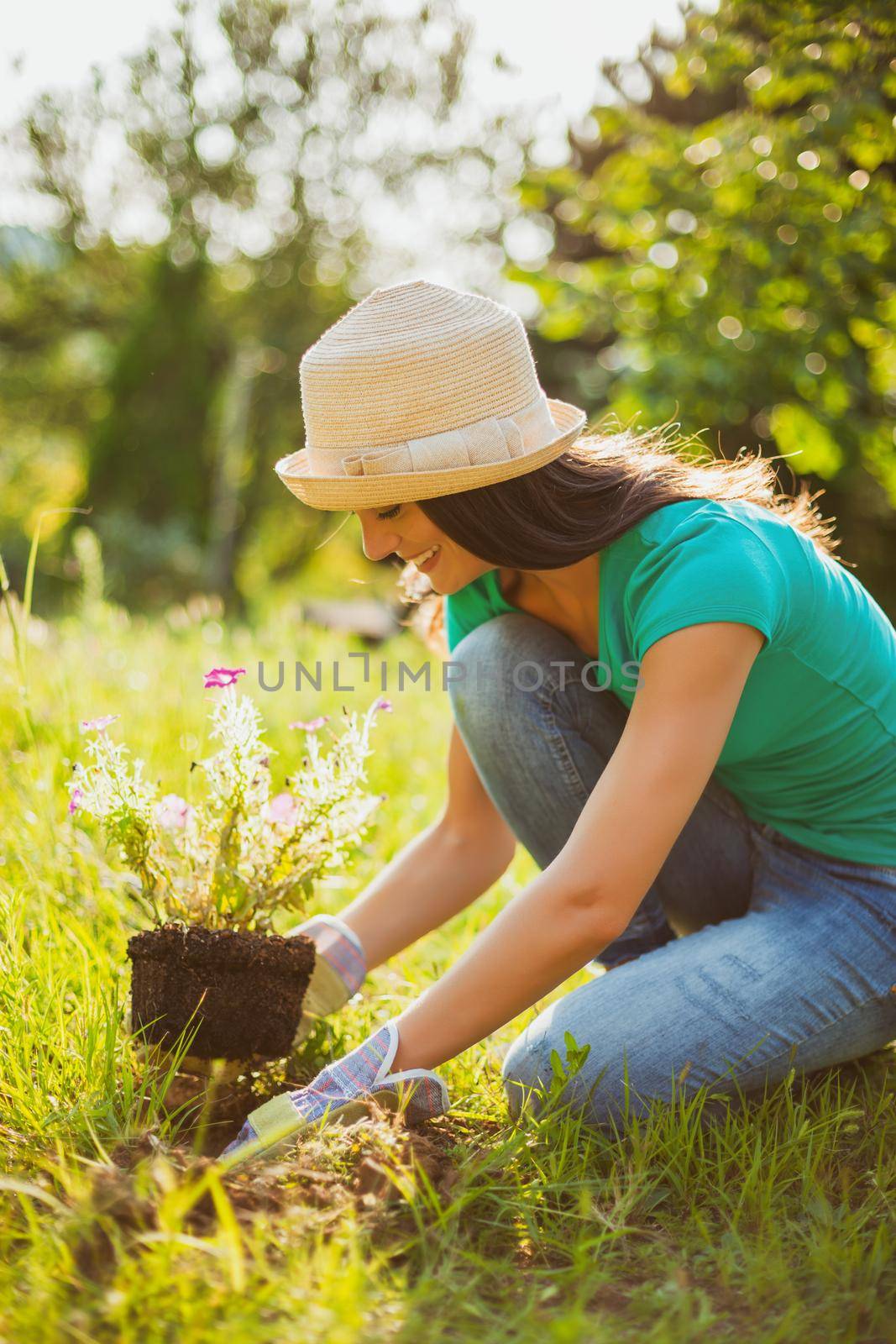 Young happy woman is planting a flower in her garden.