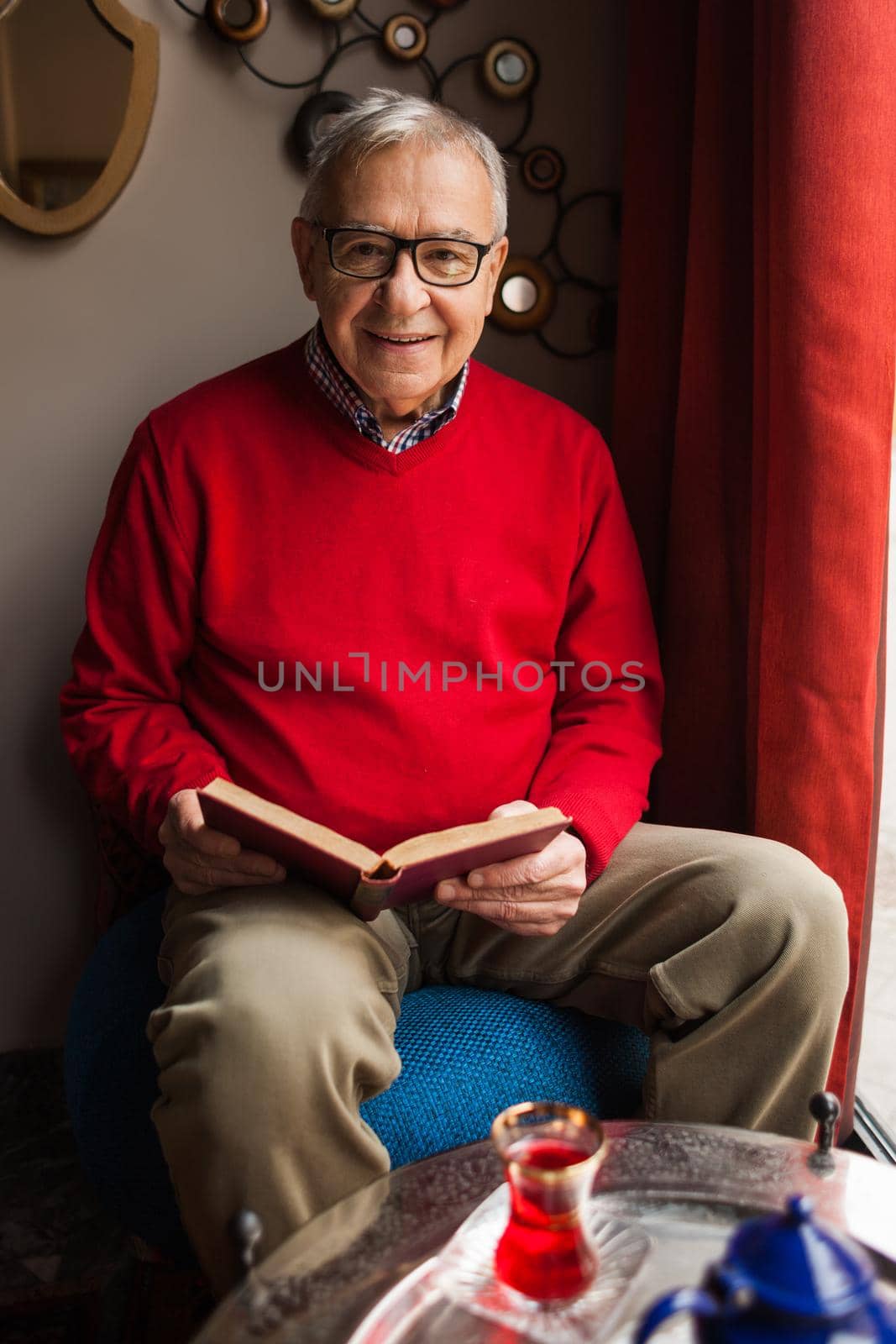 Senior man is sitting in cafe and reading a book.