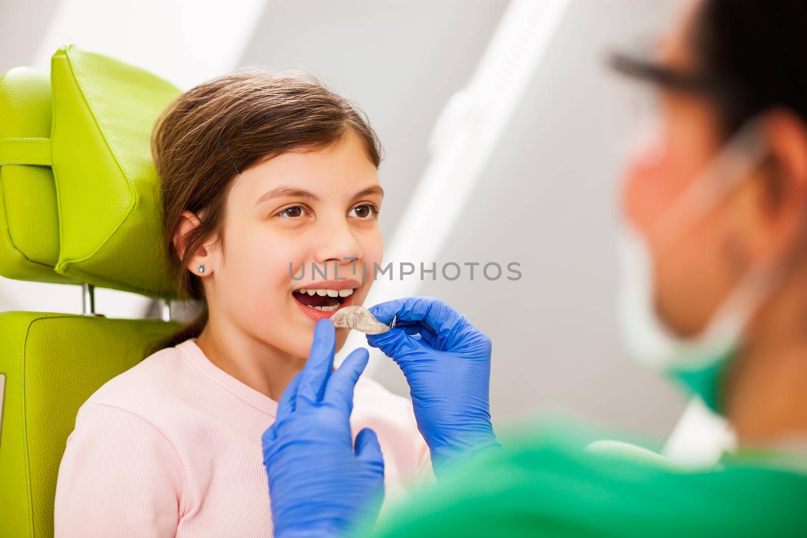 Dentist is teaching little girl about braces.