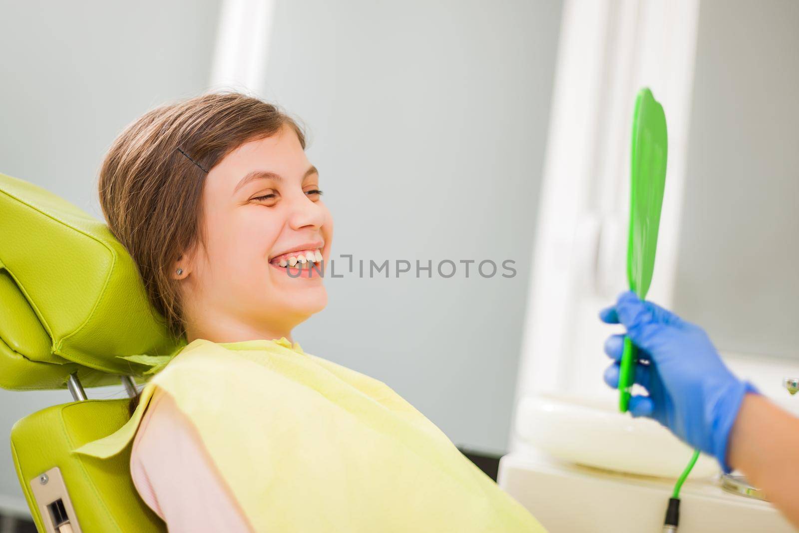 Little girl is looking at her teeth at dentist.