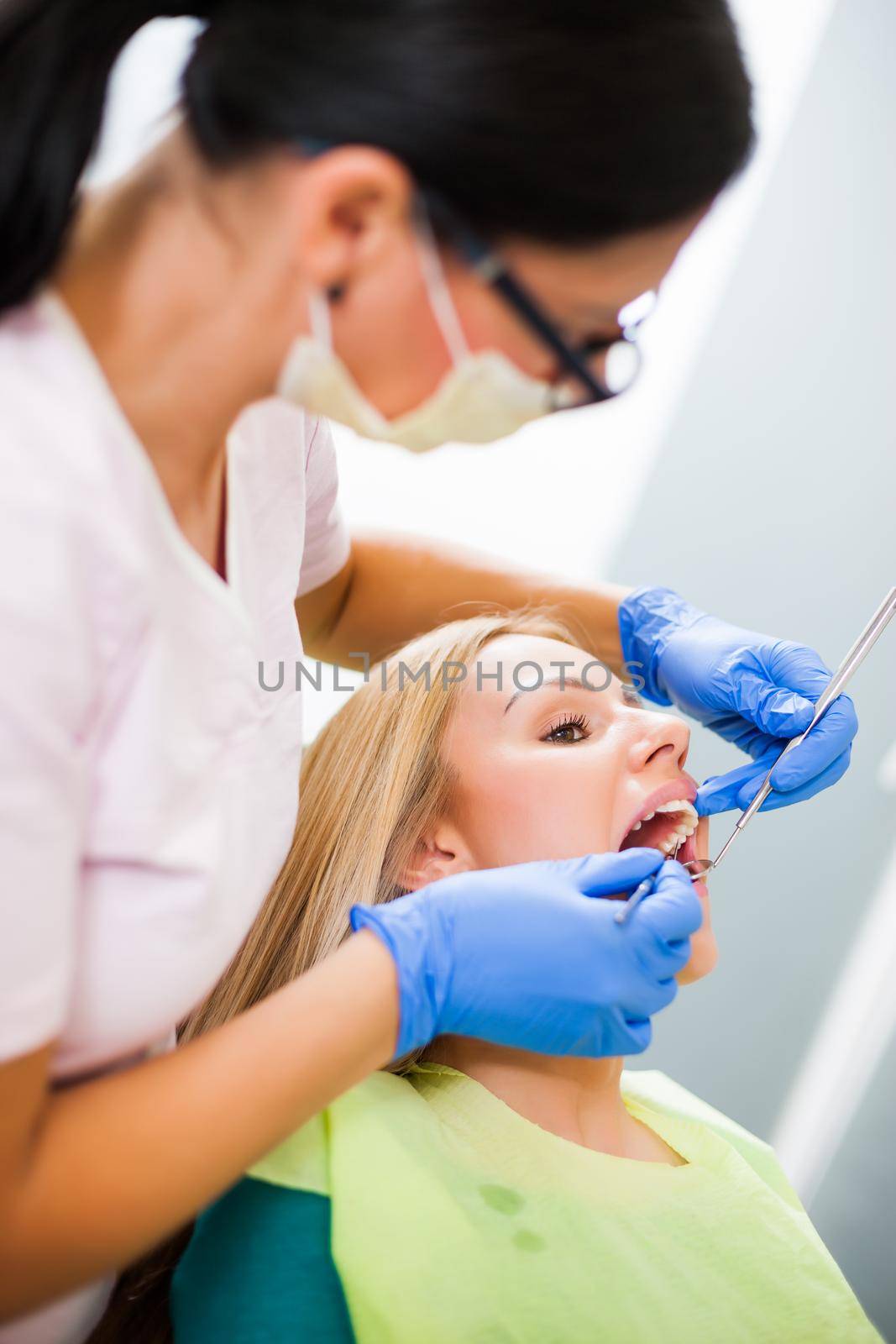 Young woman at dentist. Dentist is repairing her teeth.