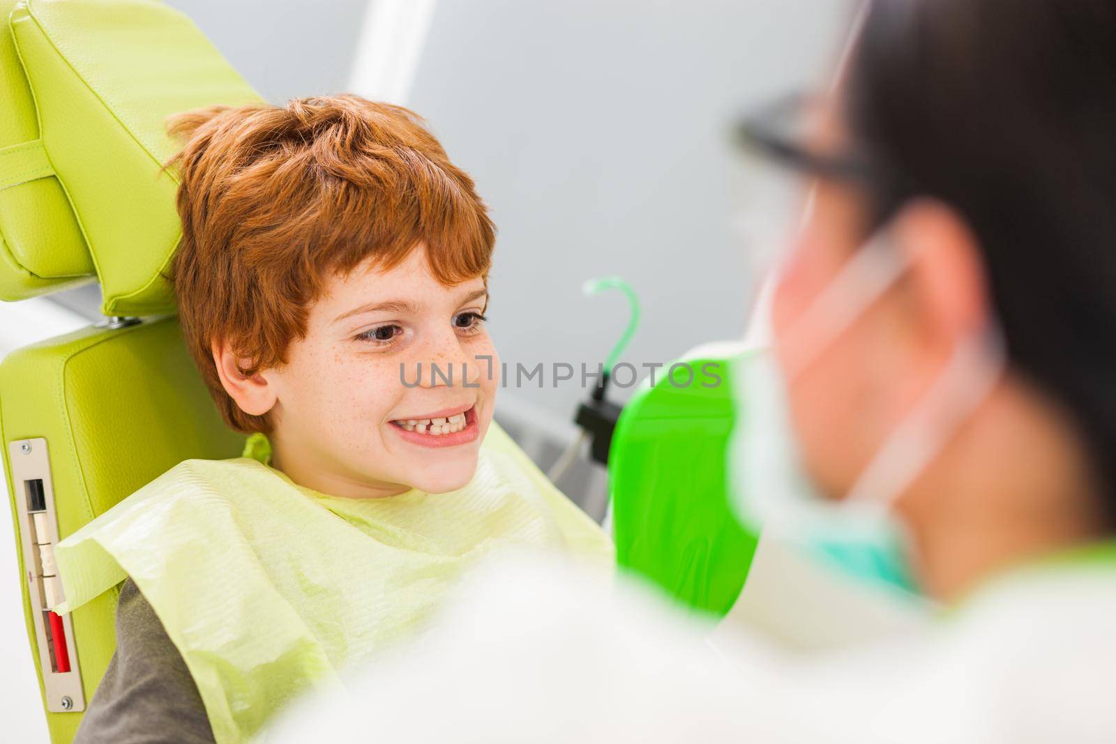 Little boy is looking at his teeth at dentist.