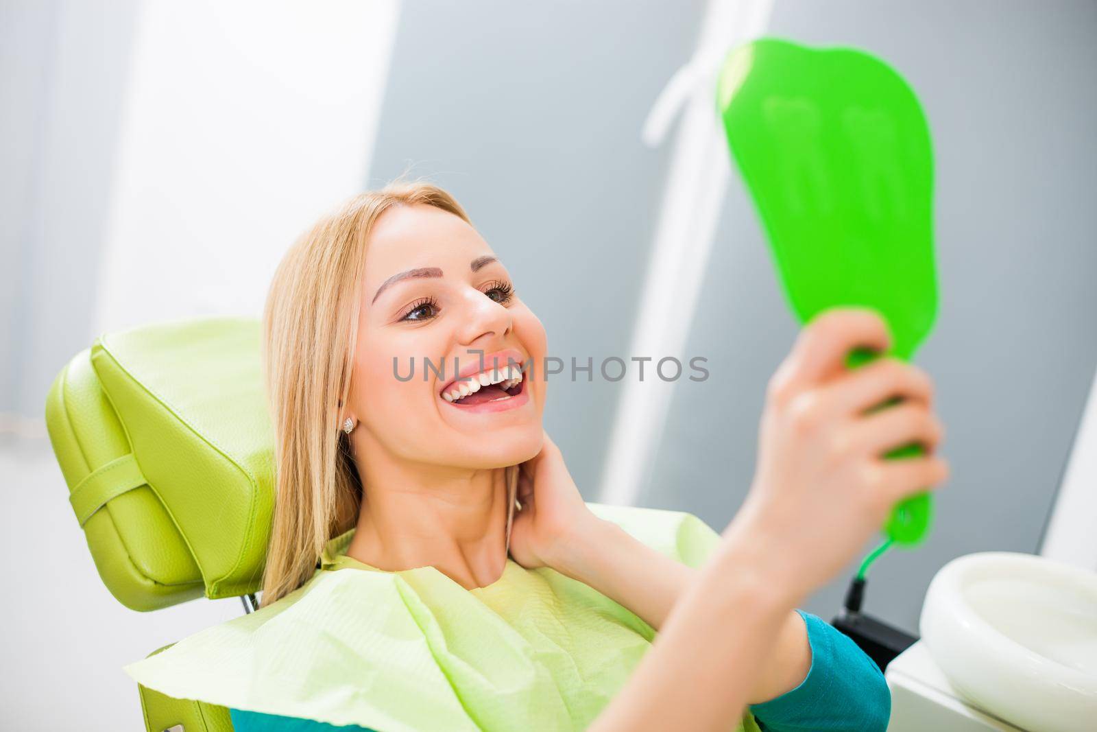 Young woman looking at her teeth after successful dental treatment.