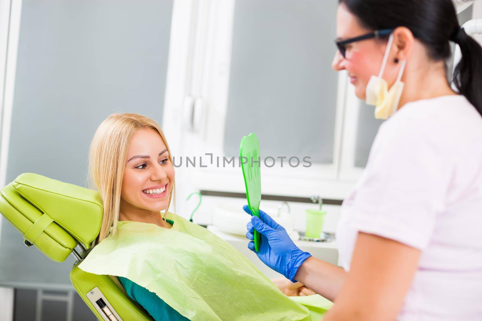 Young woman looking at her teeth after successful dental treatment.