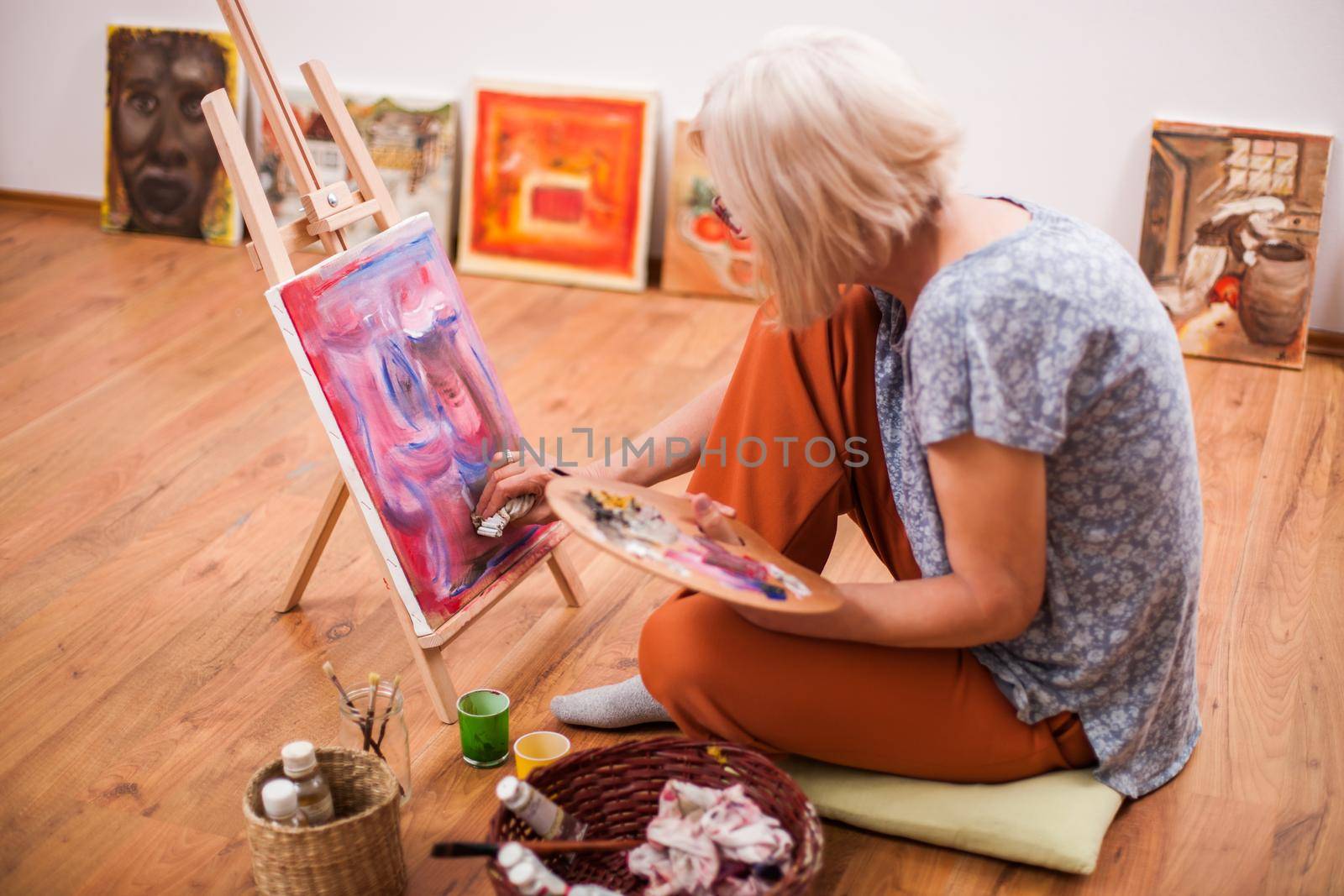 Elderly woman is painting in her home. Retirement hobby.