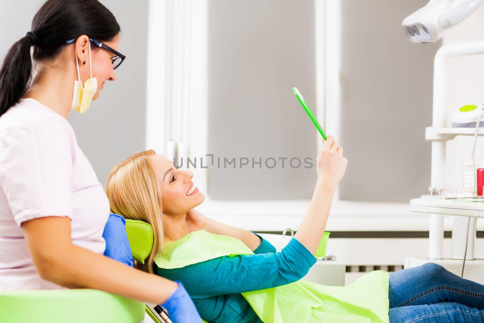 Young woman looking at her teeth after successful dental treatment.