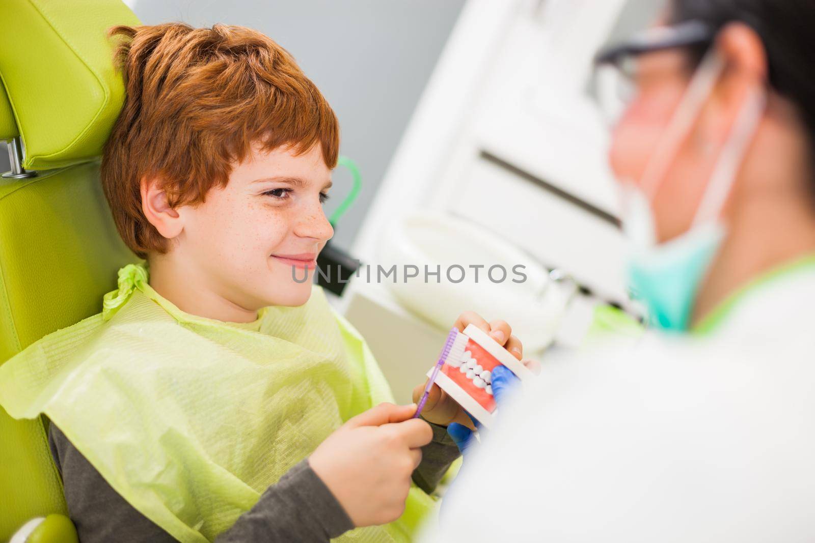 Dentist is teaching little boy about oral hygiene.