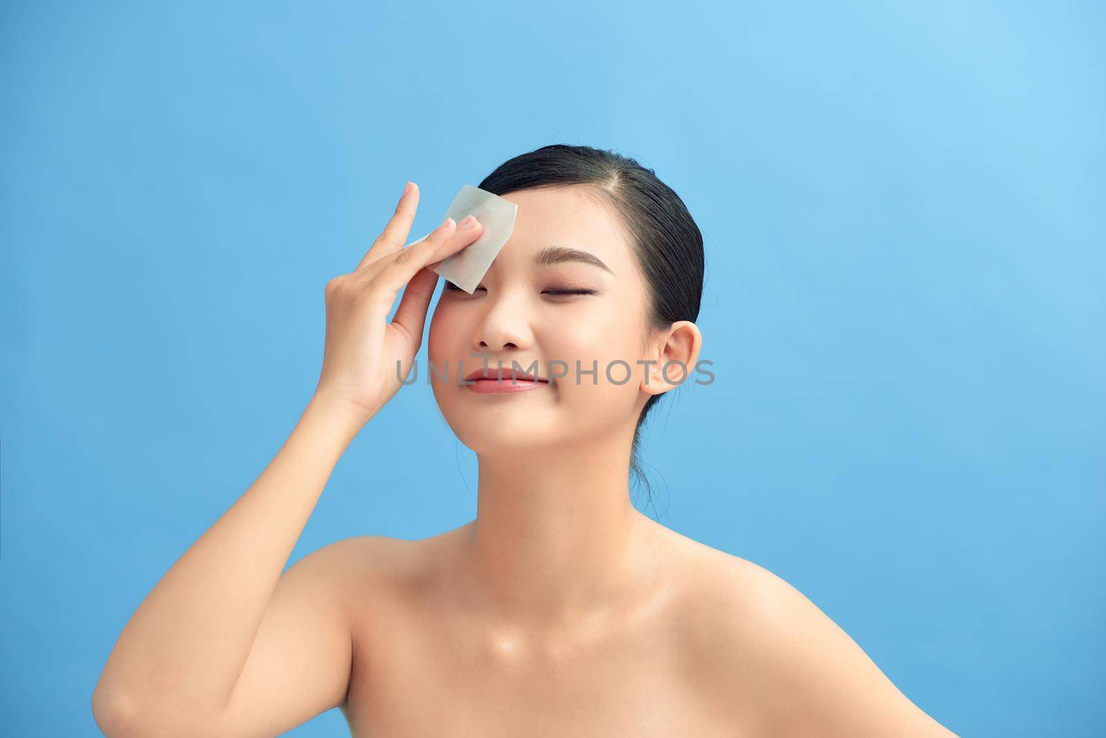 Woman removing oil from face using blotting papers
