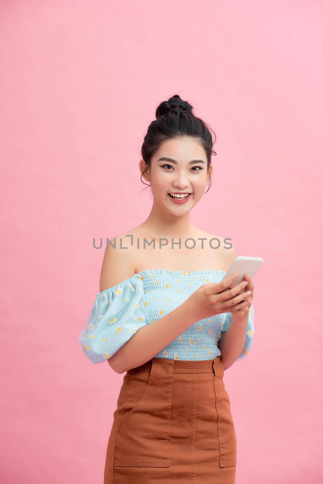 Happy cute beautiful young woman play games by mobile phone on gradient background.