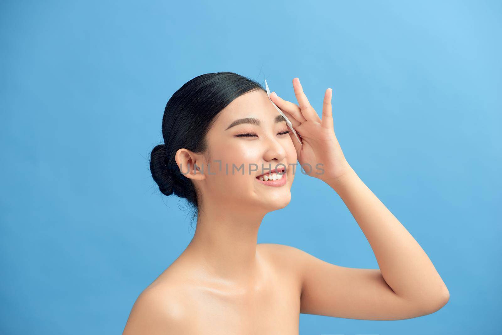 Woman using facial oil blotting paper. Beauty concept