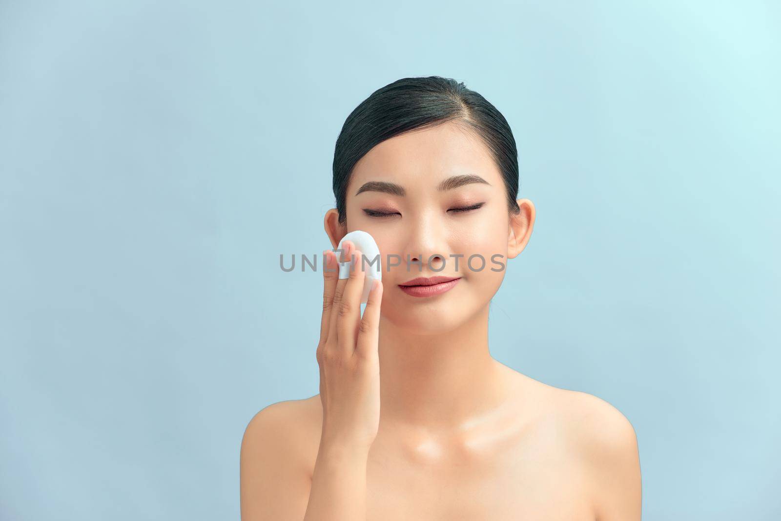 Woman applying cosmetic powder on face by makidotvn
