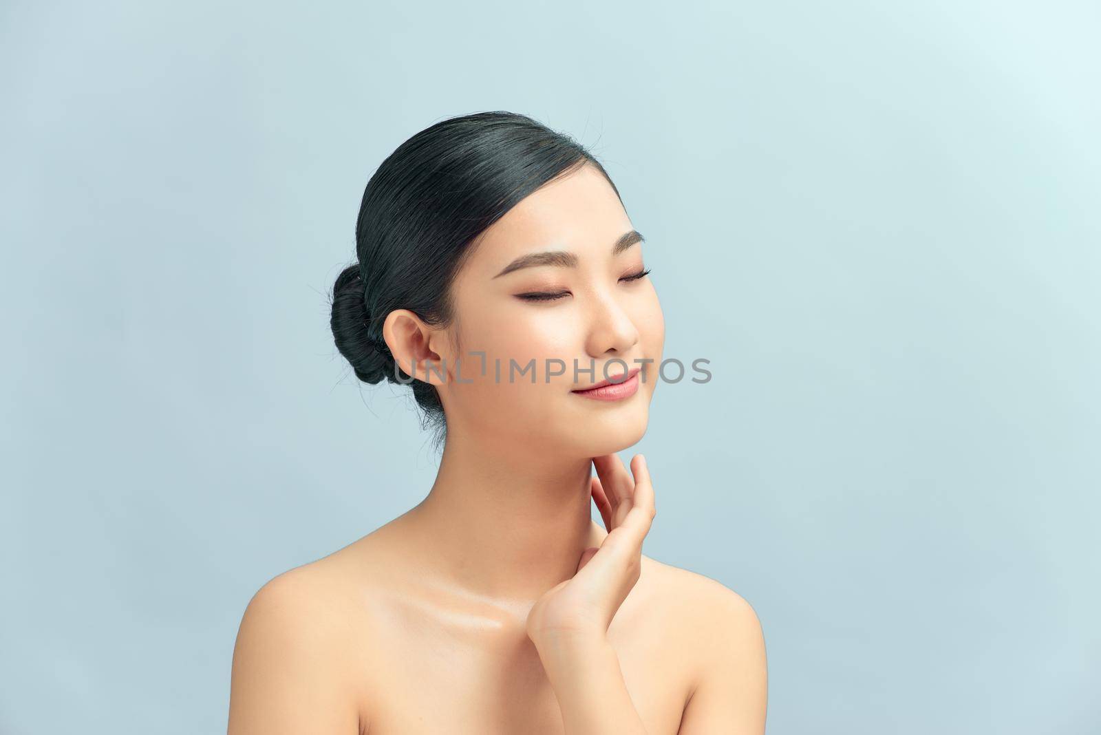 asian young beautiful woman smiling and touching her neck. isolated on light background.