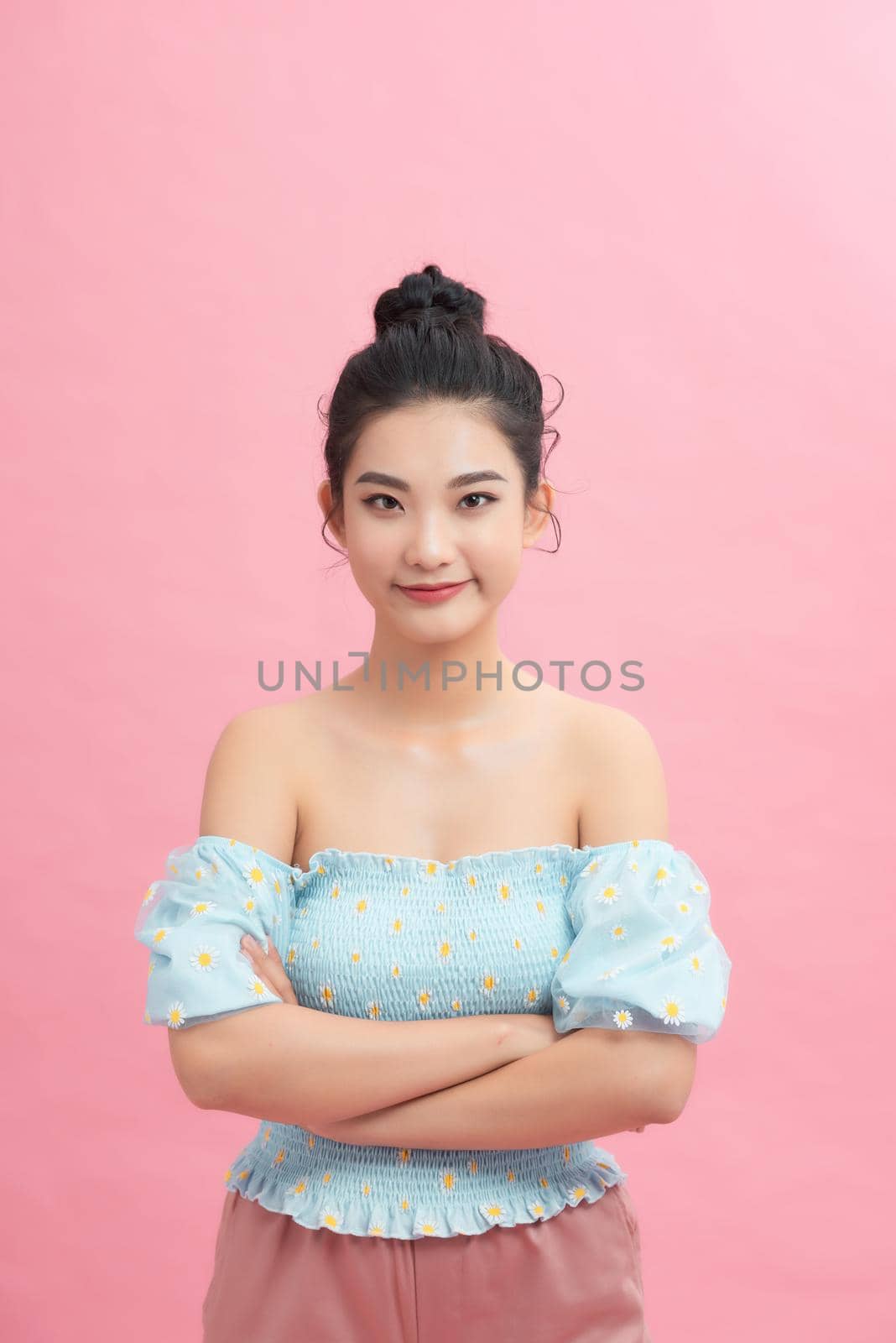 Smiling beautiful woman portrait with crossed arms on pink background by makidotvn