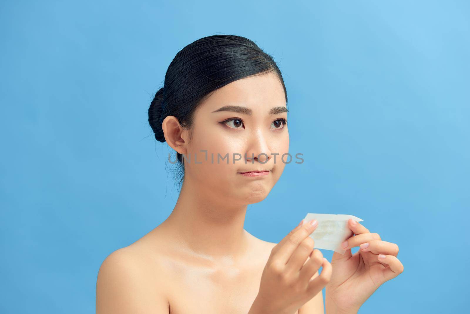 Young asian skin care woman upset after use oil blotting paper on her face by makidotvn