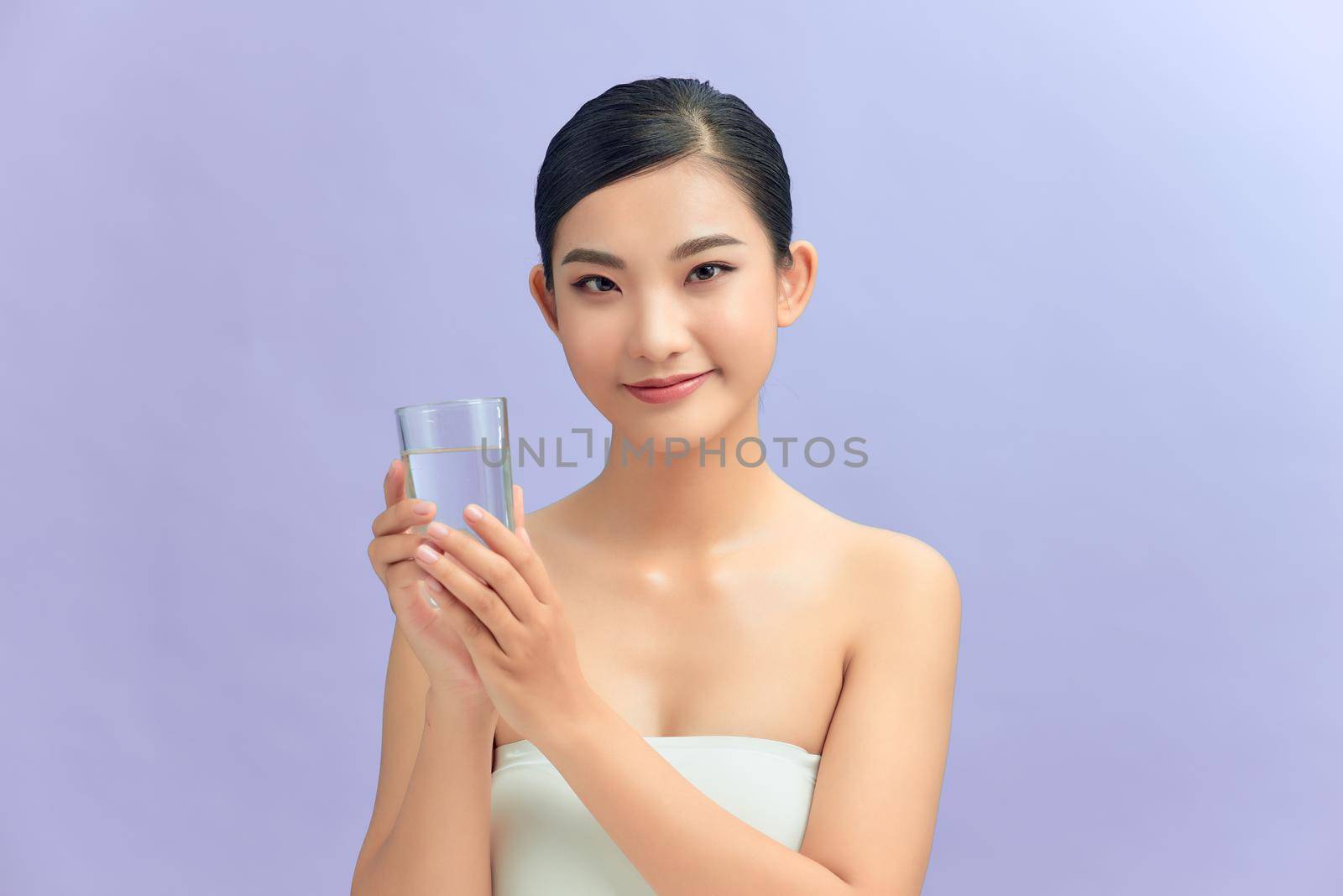 Young beautiful woman drinking water from glass. Isolated on white background