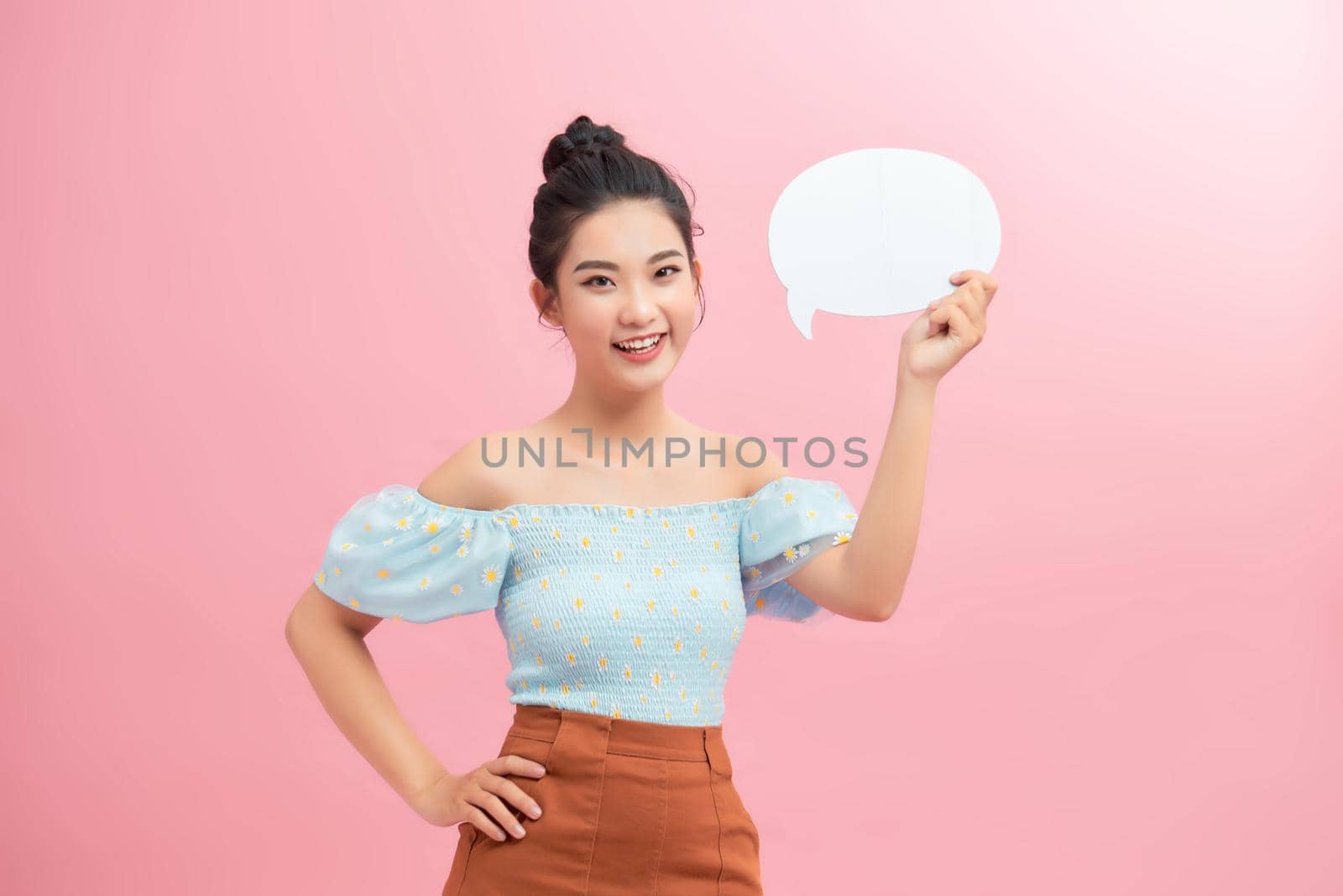 Young beautiful girl holding a white bubble for text, isolated on a pink background by makidotvn