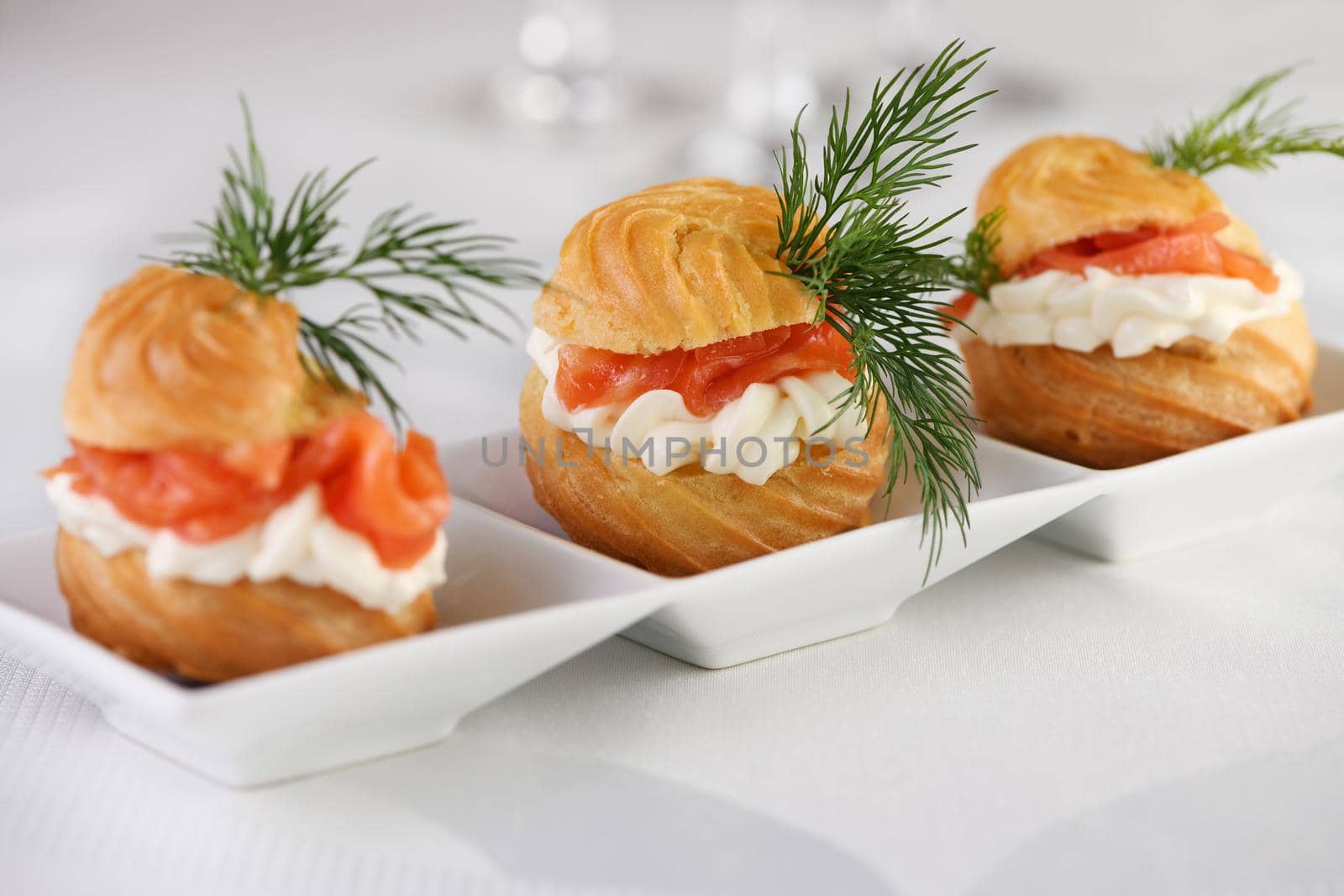 Profiteroles stuffed with cream cheese and salmon, decorated with a sprig of dill. Close-up 