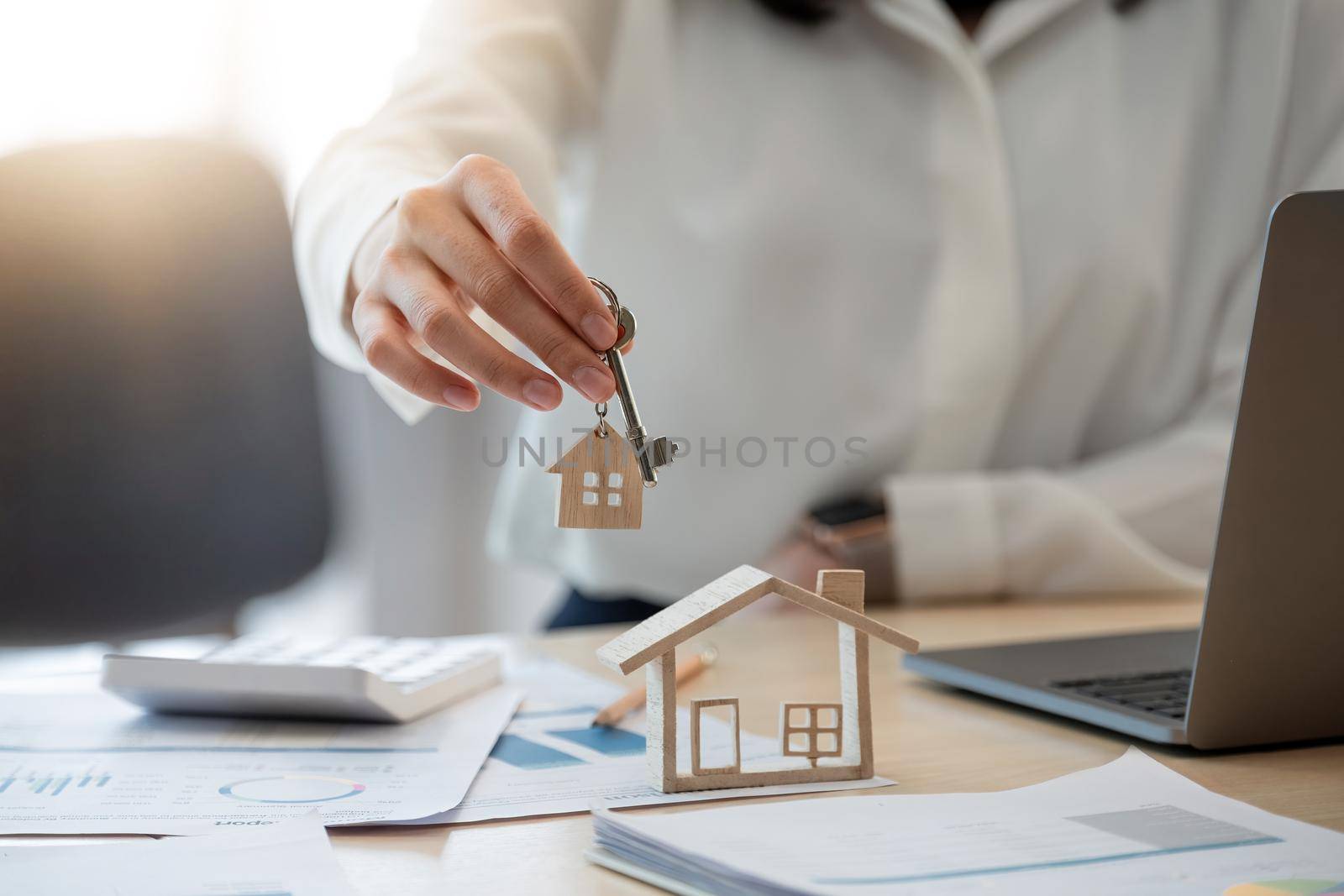 Female hand holding house key,real estate agent woman working house loan at her office by nateemee