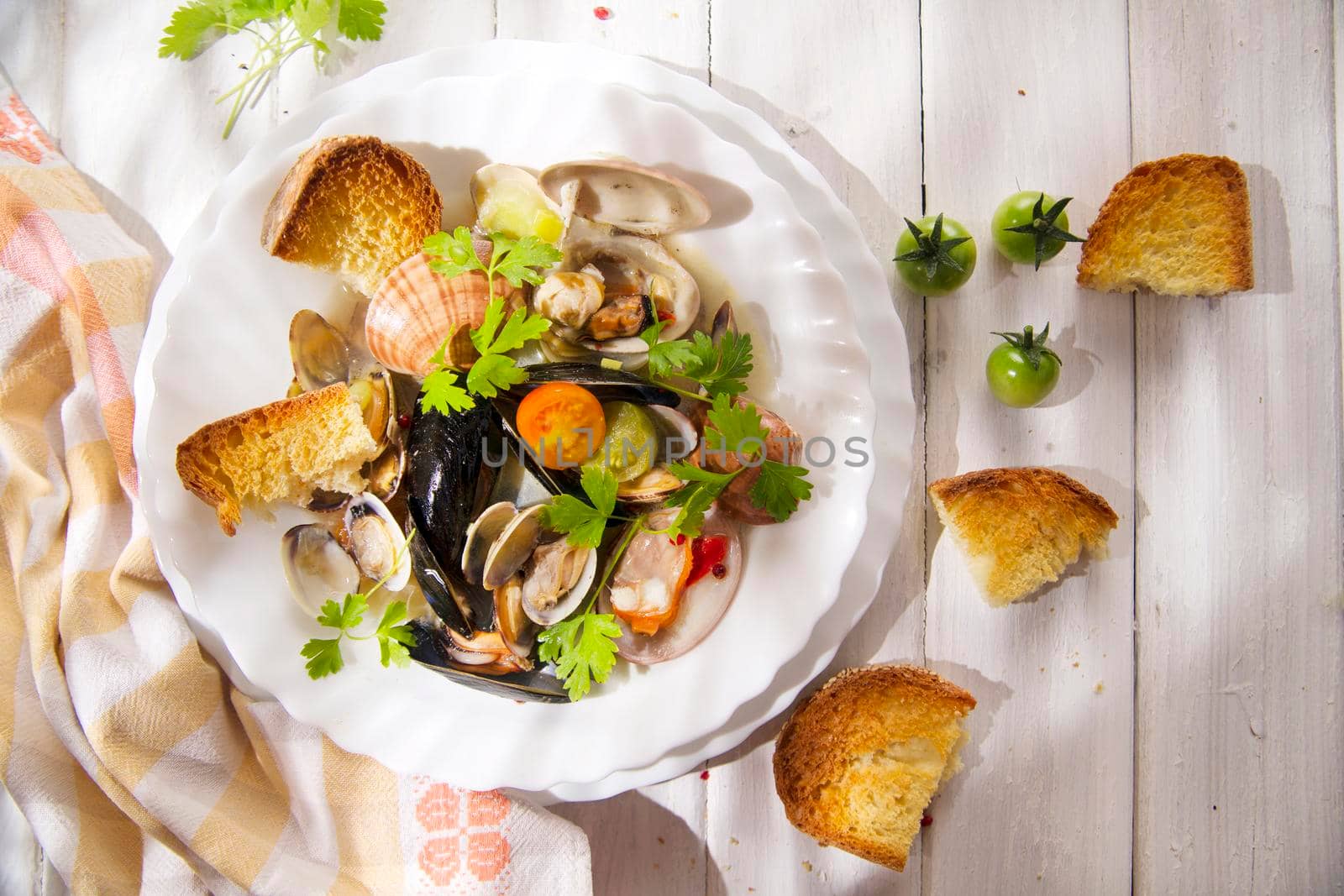 Presentation of a soup with seafood with roasted bread