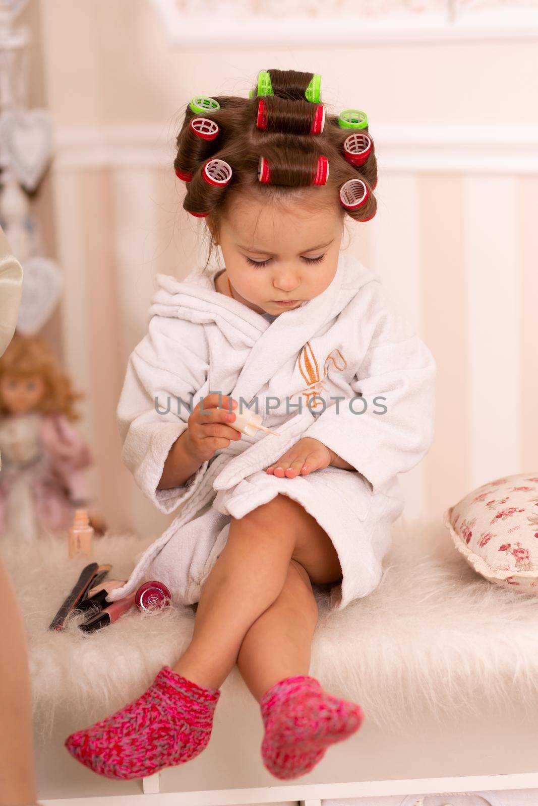 Adorable little girl with curlers paints her fingernails. Copies mom's behavior. Young fashionista. Beauty day by Try_my_best